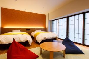 una habitación de hotel con dos camas y una mesa en 城崎温泉お宿白山花まんだら, en Toyooka