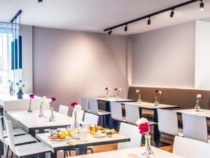 a dining room with white tables and white chairs at B&B Hotel Regensburg-City in Regensburg