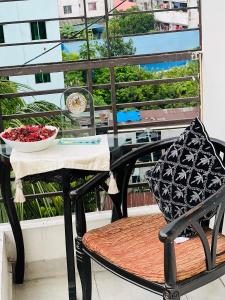 Una mesa y una silla con un jarrón de flores en un balcón. en Gulshan Guest House, en Dhaka
