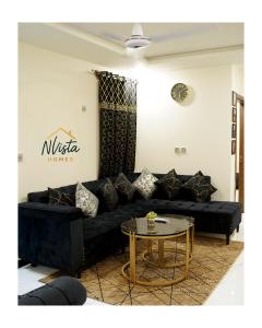 a living room with a black couch and a table at Nvista Luxe Living in Islamabad