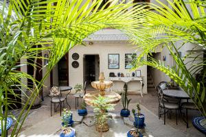 un patio con una fuente, sillas y plantas en Riad Chams Marrakech, en Marrakech