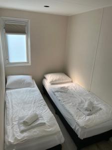 Dos camas en una habitación pequeña con ventana. en Bosperceeltje Putten, en Putten