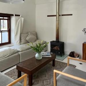 a living room with a couch and a table with a fireplace at Watsonia Cottage at Waboom Family Farm in Stanford