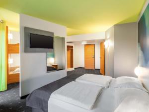 a bedroom with two beds and a flat screen tv at B&B Hotel Krefeld in Krefeld