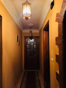 einen Flur mit einer schwarzen Tür und einem Kronleuchter in der Unterkunft Cleopatra hostel -埃及艳后 民宿 in Kairo