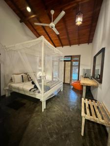 a bedroom with a white bed with a ceiling fan at Rowinrich Cottages in Ella