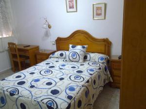 a bedroom with a bed with a blue and white comforter at Hostal Asensio Nijar in Níjar