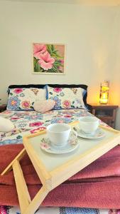 una mesa con dos tazas y platos en una cama en Floripa espaço independente com próx Centro e UFSC, en Florianópolis