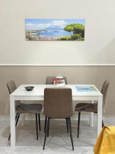 a white table and chairs with a painting on the wall at Casa Vacanza da Rosy in Boscotrecase