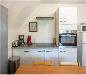 a kitchen with white cabinets and a table and a counter at Appart 8 personnes Jardin Parkings Voitures Vélos,10min Château,40min Zoo Beauval in Blois +29 photos