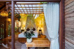 a bedroom with a bed in a window with a plant at Yeh Pulu House in Ubud