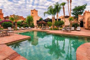 a swimming pool with tables and chairs in a courtyard at Ksar Ighnda in Aït Ben Haddou