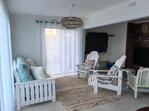 a living room with white chairs and a tv at Seaside Escape in Pearly Beach
