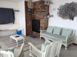a living room with chairs and a couch and a fireplace at Seaside Escape in Pearly Beach