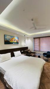 a bedroom with a large white bed and a living room at Casa Nova Luxury Studio and Prime Location in Greater Noida