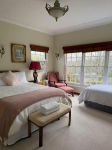 a bedroom with two beds and a chair and windows at Echo point Cottage in Katoomba