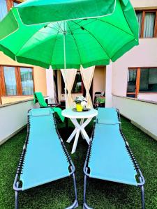 a table and two chairs with a green umbrella at Apartment - Studio Cucetno in Sandanski
