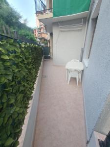 eine Terrasse mit einer weißen Bank und einer grünen Hecke in der Unterkunft Casa gioiello al mare Cogoleto in Cogoleto