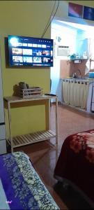 Una habitación con una mesa y un televisor en la pared. en Hospedaje Los Buenos Aires, en Santa Ana