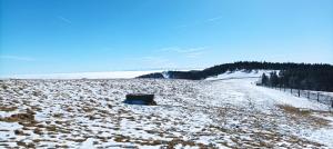 a snow covered field with a fence and a road at Au relais des ballons in Saint-Maurice-sur-Moselle