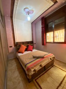 a bedroom with a bed with red pillows and a window at maison de bonheur in Tafraoute