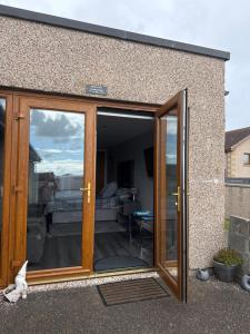 an open sliding glass door of a house at Wee Coastal Snug in Wick