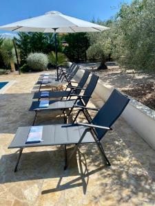 a row of lounge chairs with an umbrella at Villa hygge in Šibenik
