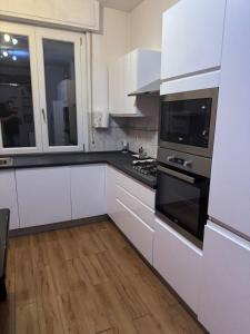 a kitchen with white cabinets and black appliances at Easy Room Italy Central Station in Milan +7 photos