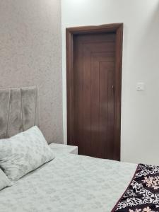 a bedroom with a bed and a wooden door at 2nd Home Apartments in Faisalabad