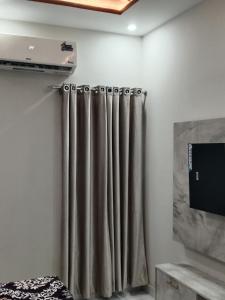a shower curtain in a room with a tv at 2nd Home Apartments in Faisalabad