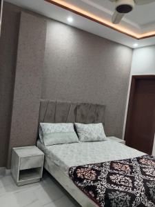 a bedroom with a bed and a night stand at 2nd Home Apartments in Faisalabad