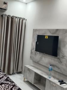 a living room with a tv and a couch with curtains at 2nd Home Apartments in Faisalabad
