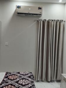 a room with a bed and a heater and curtains at 2nd Home Apartments in Faisalabad