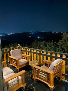 two chairs and a table on a balcony at night at منتجع غروب الشمس in Ajloun