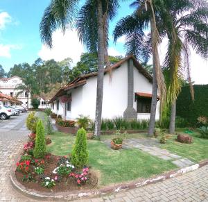 a house with palm trees and flowers in front of it at Pousada do Sol in Penedo