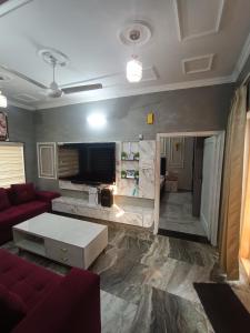 ein Wohnzimmer mit einem roten Sofa und einem Fernseher in der Unterkunft The family courtyard in Amritsar