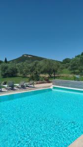 a swimming pool with chairs and a mountain in the background at Domaine du Moulin de Cors in La Roque-sur-Cèze