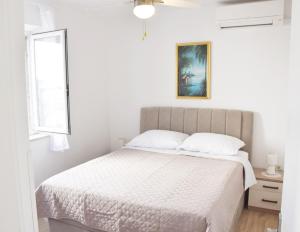 a white bedroom with a bed and a window at Apartments Vulicevic in Dubrovnik