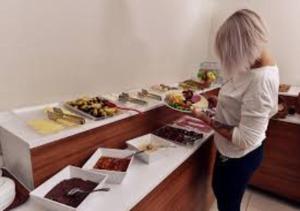 a woman holding a plate of food at a buffet at Rays Hotel - Bakirkoy Istanbul City Center in Istanbul