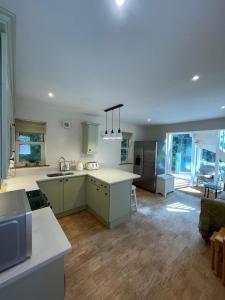 a kitchen with green cabinets and a living room at Luxury Woodland Stay in Cheltenham in Cheltenham