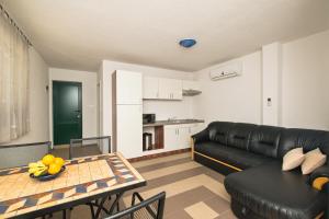 a living room with a black leather couch and a table at Apartment Afrika in Makarska