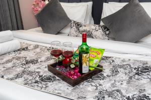 a tray with two glasses and a bottle of wine on a table at Private Cinema Apartment By Buddies Home in Greater Noida