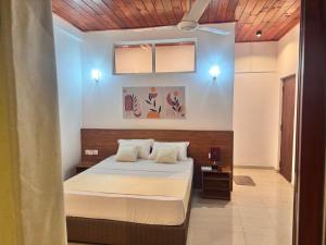 a bedroom with a bed with white sheets at Misty Hills Lakeview Lounge in Kandy +289 photos