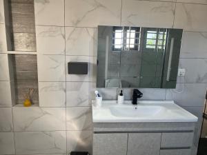 a white bathroom with a sink and a mirror at 1BR Ultra Modern Apartment in Gbawe in Gbawe +5 photos