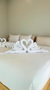 ein weißes Bett mit weißen Handtüchern darauf in der Unterkunft Hill Jai Poolvilla Khao Kho in Khao Kho