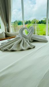 eine weiße Decke auf einem Bett mit einem Fenster in der Unterkunft Hill Jai Poolvilla Khao Kho in Khao Kho