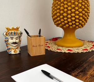 a desk with a cup of pens and a vase with a pineapple at Etna Docet in Nicolosi