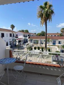 a balcony with a table and chairs and a palm tree at Perla Marina in Marina di Sibari