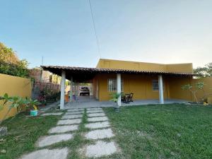 a small yellow house with a patio in the yard at Lar de Maria Aguiar in Barreirinhas