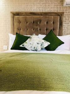 Cama con sábanas y almohadas verdes y blancas en Makhasana, 